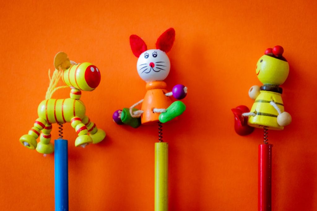 Close-up of three colorful wooden toys on a vibrant orange background, perfect for childrens themes.